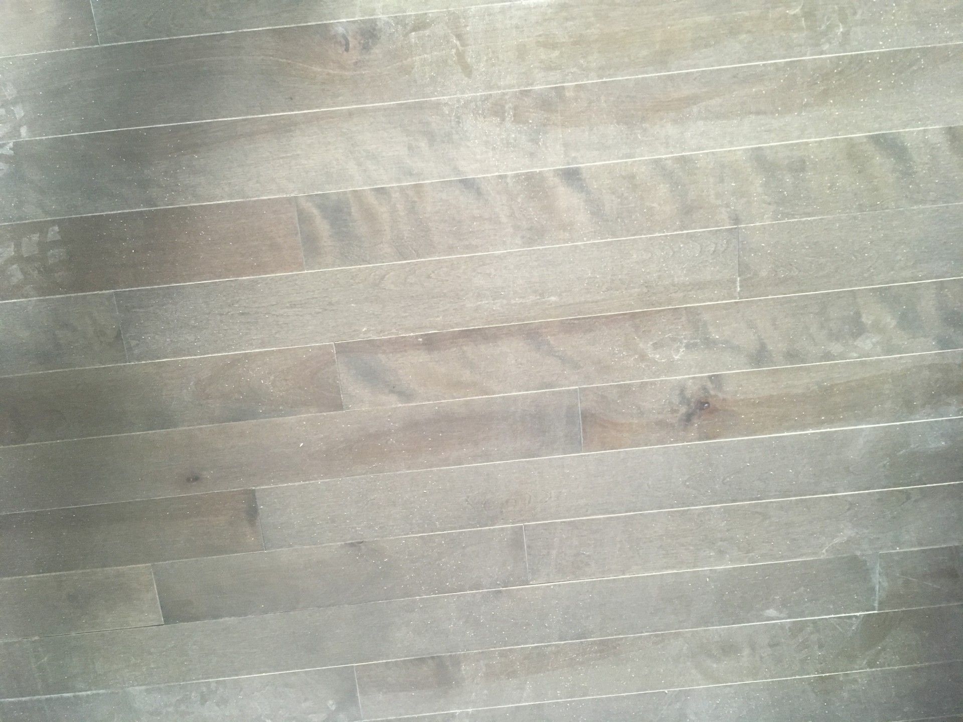 Plancher en bois, brun clair avec un grain subtil, horizontal avec des lignes pointillées blanches entre les lames.