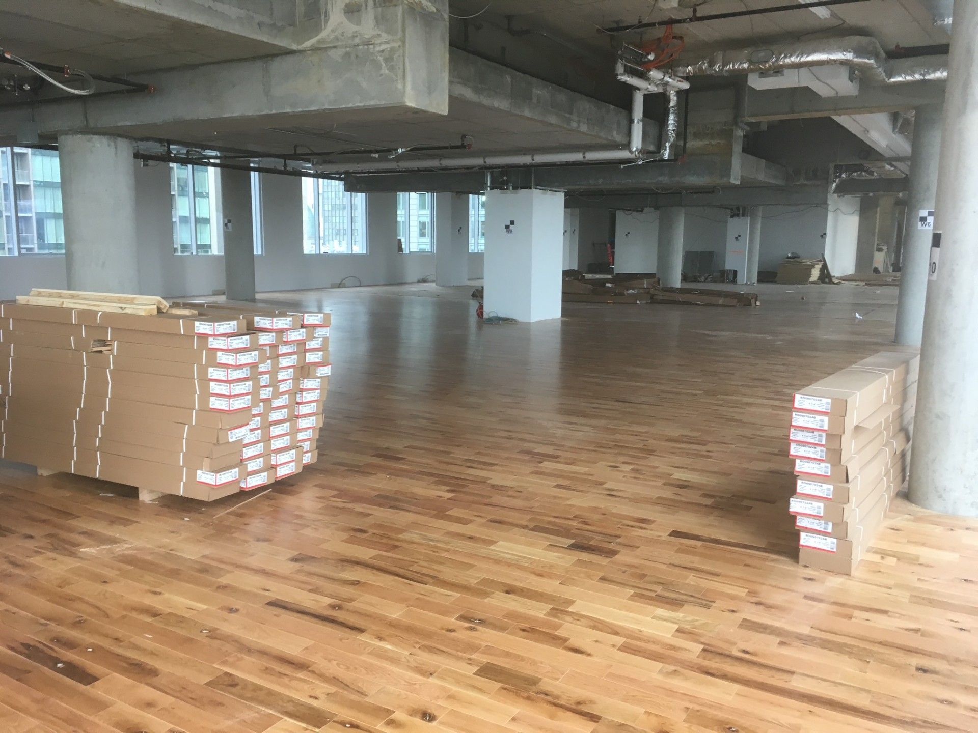 Pièce vide avec parquet, matériaux de construction et structure de plafond apparente.