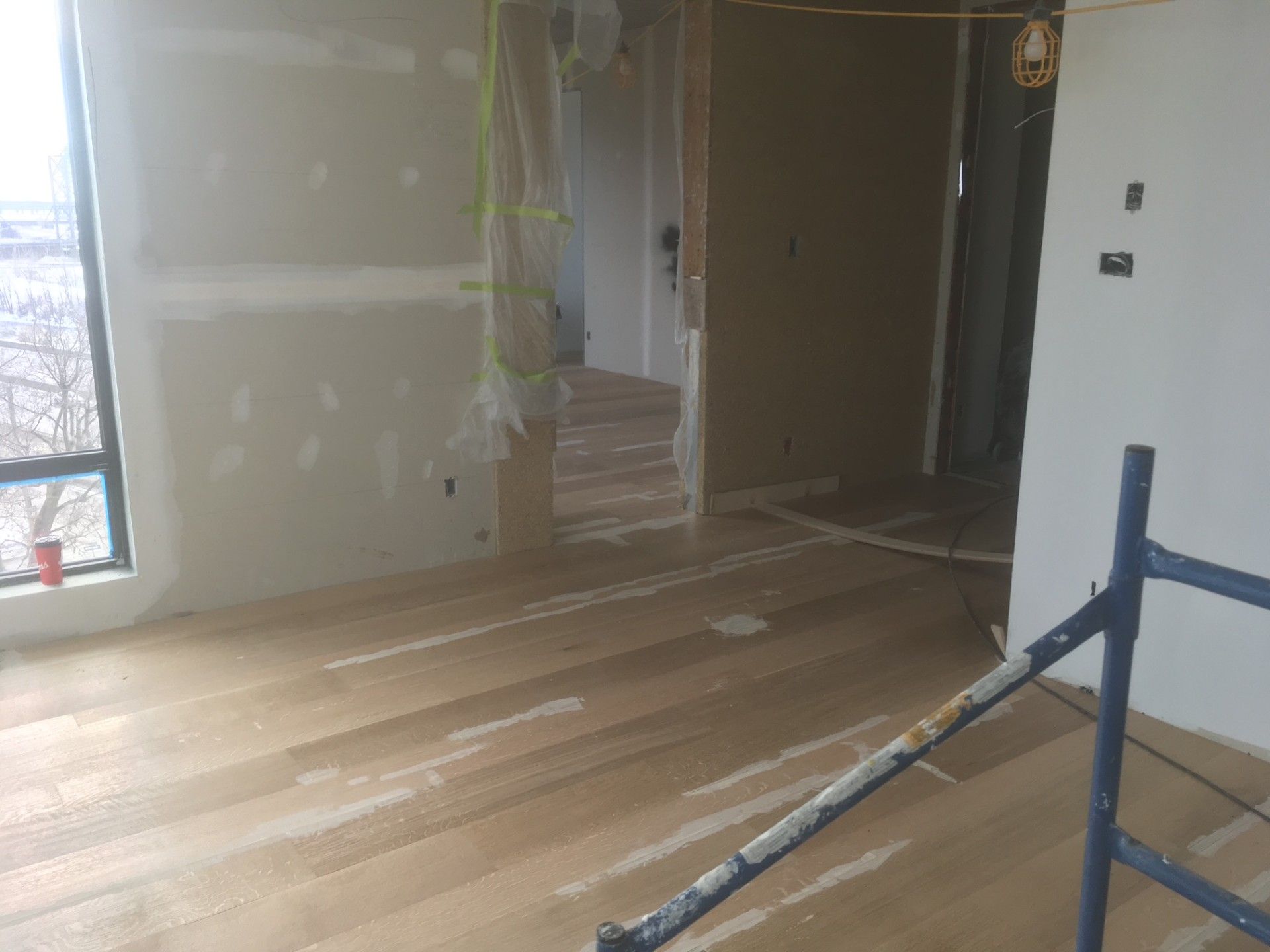 Pièce intérieure en construction, avec parquet, cloisons sèches et une porte partiellement obstruée.