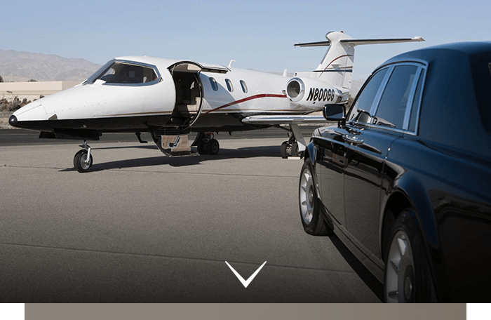 White private jet parked on a runway beside a black limousine, with desert mountains in the background