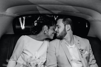 Couple in wedding attire sharing an intimate kiss in the back seat of a car