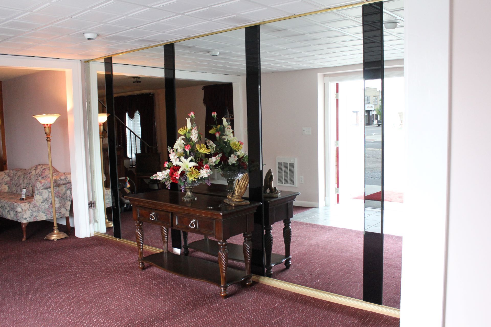 A room with a table and mirrors and a vase of flowers on it