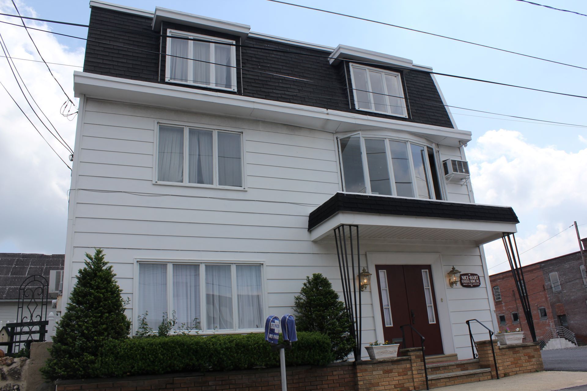 A white house with a black roof has a blue mailbox in front of it