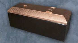 A black box with a copper lid is sitting on a blue surface.