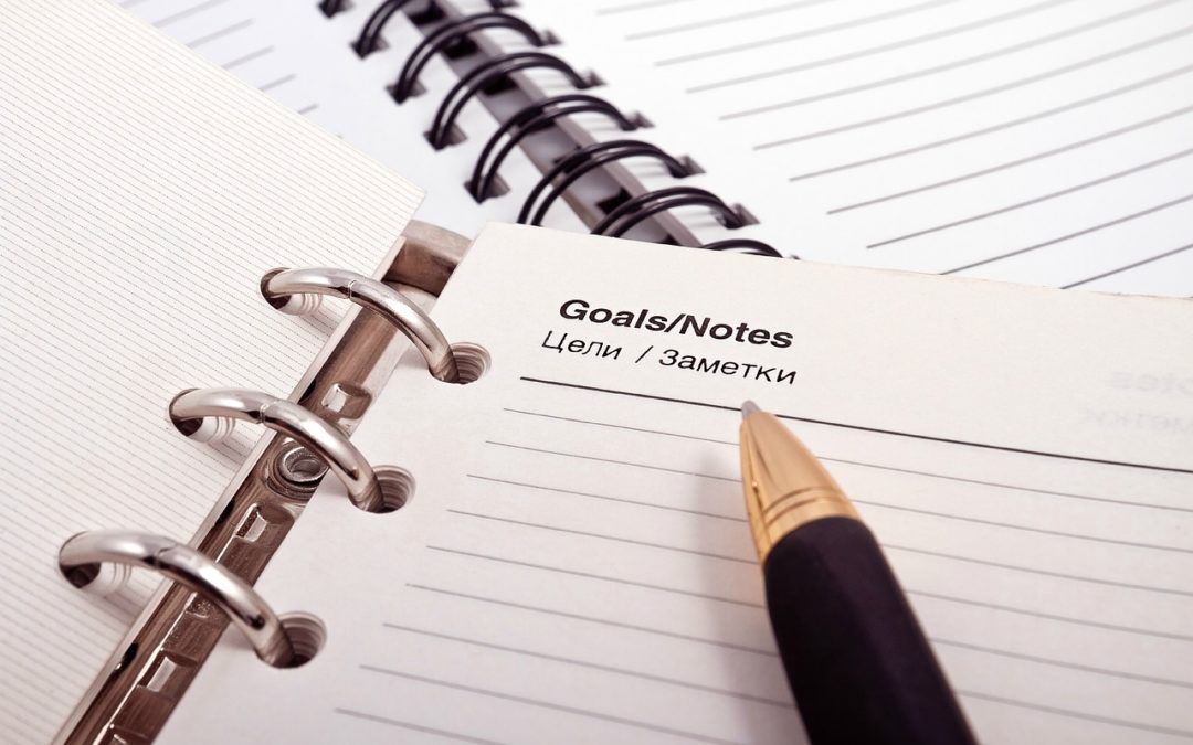 A pen is sitting on top of a spiral bound notebook.