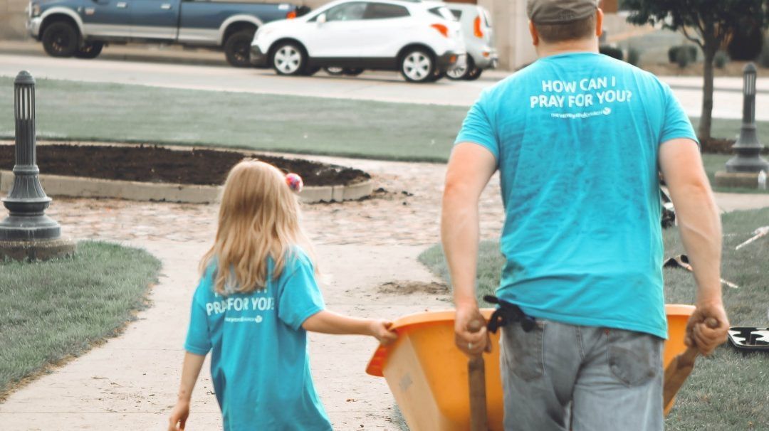A man and a little girl are walking down a sidewalk holding hands.