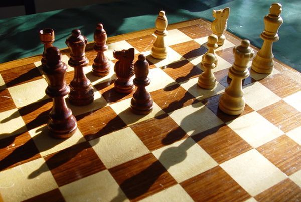 A wooden chess board with chess pieces on it