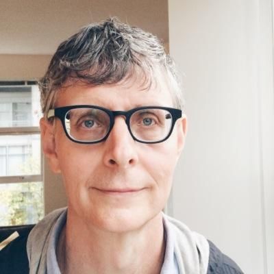 A man wearing glasses is smiling for the camera.