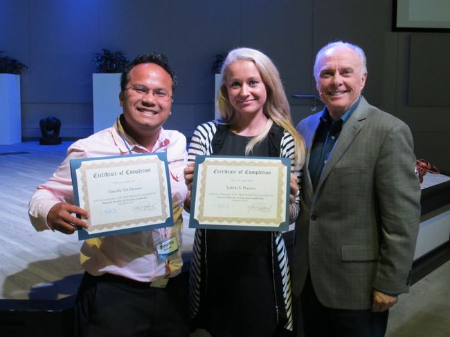 Dr. Mark Rutland standing with two graduates holding certificates in their hands