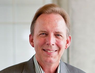 A man in a suit and striped shirt is smiling for the camera.