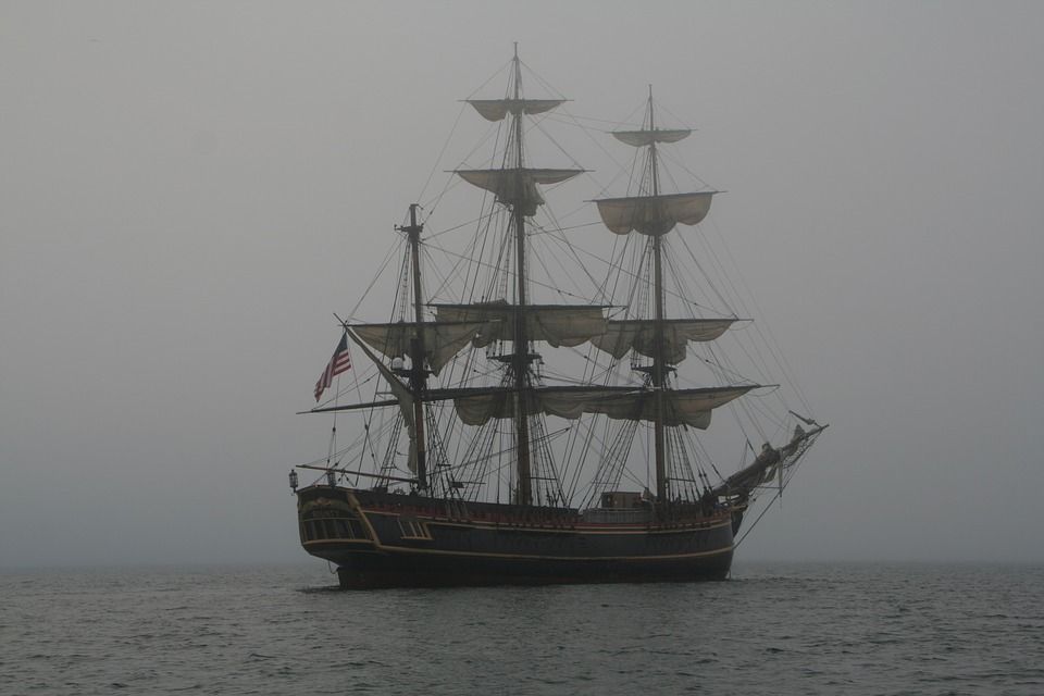 A pirate ship is floating on top of a foggy ocean.