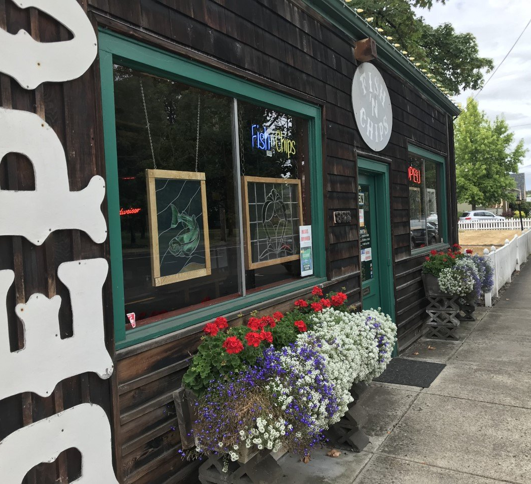 A wooden building with green trim, flower boxes, and a sign.