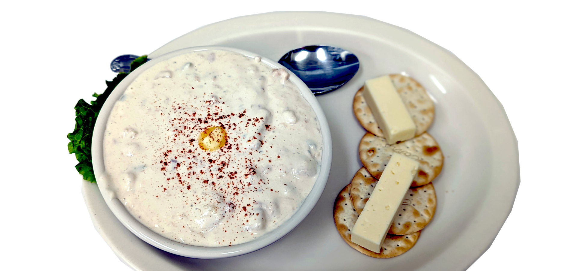 Clam chowder with crackers and butter on a white plate.