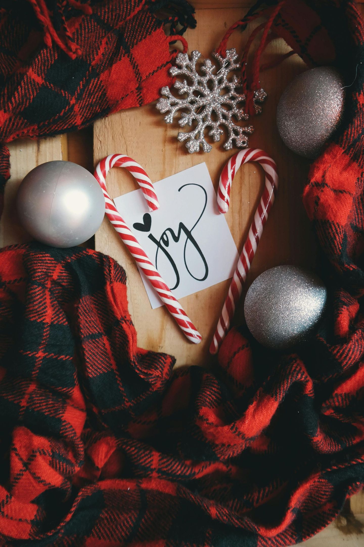 Red and Black plaid scarf with two striped candy canes Joy written on white paper