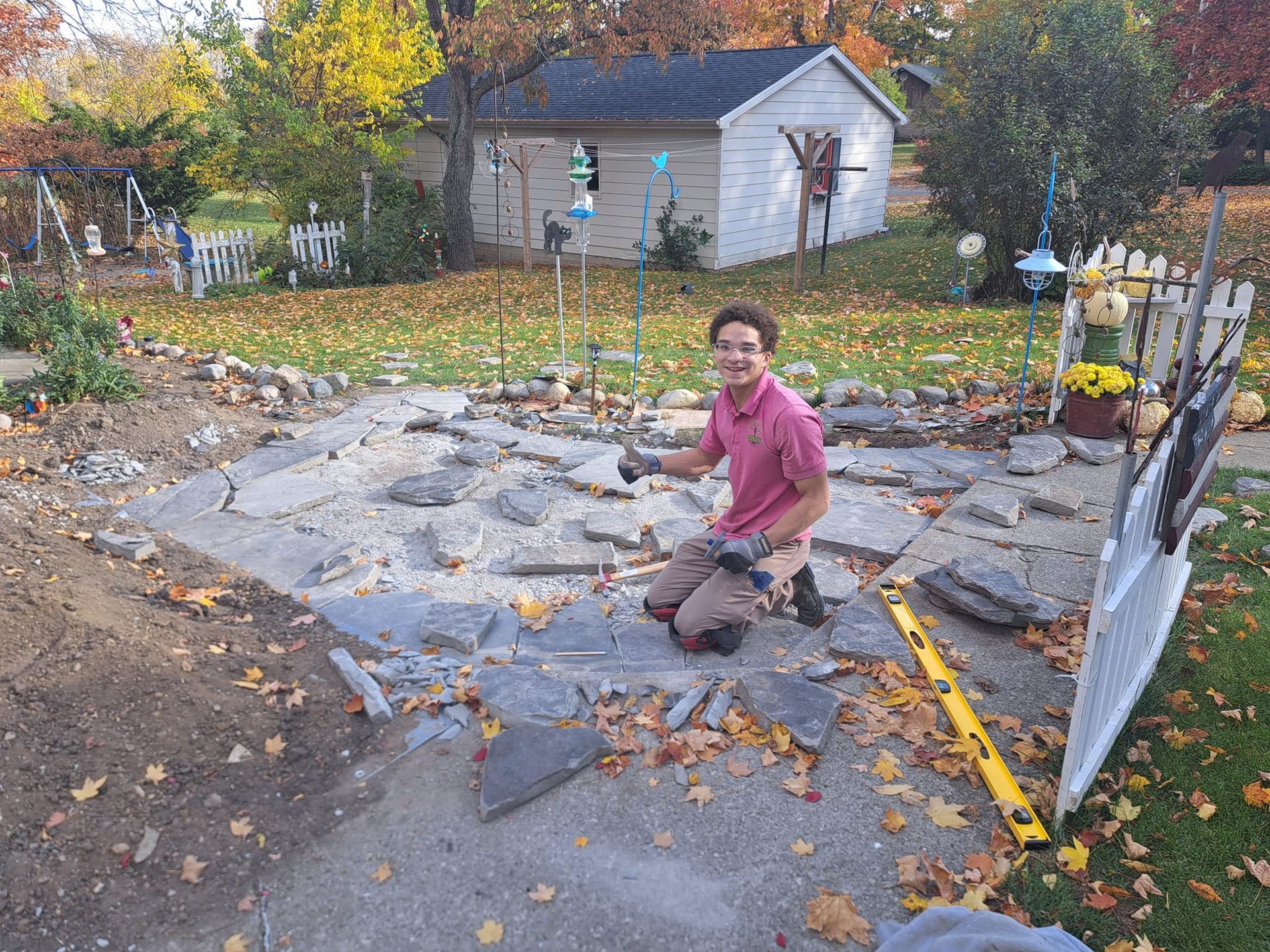 A man is kneeling on the ground holding a hammer.