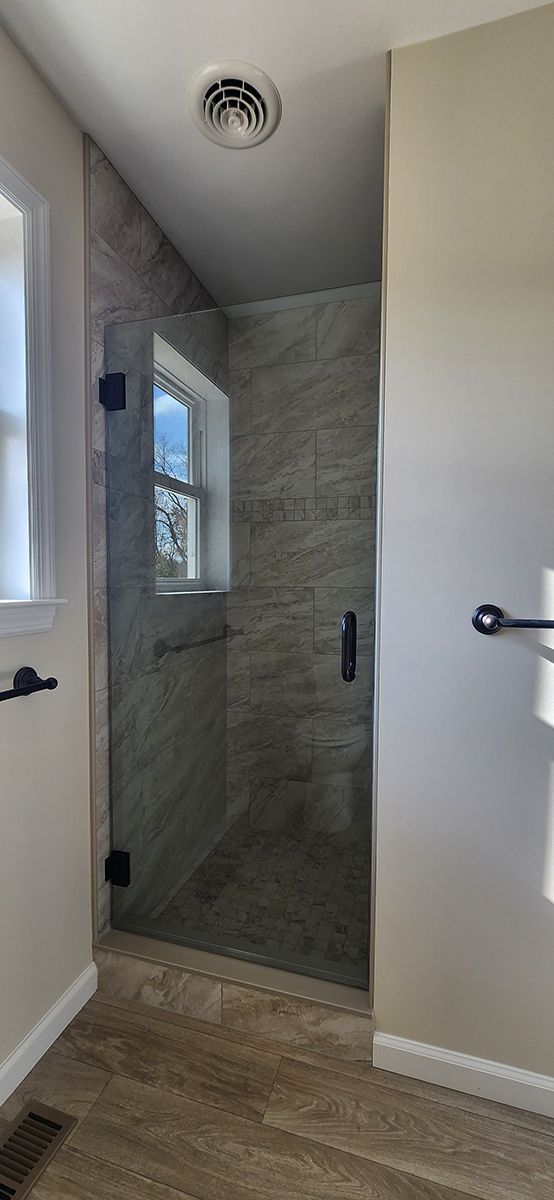 A bathroom with a walk in shower and a window.
