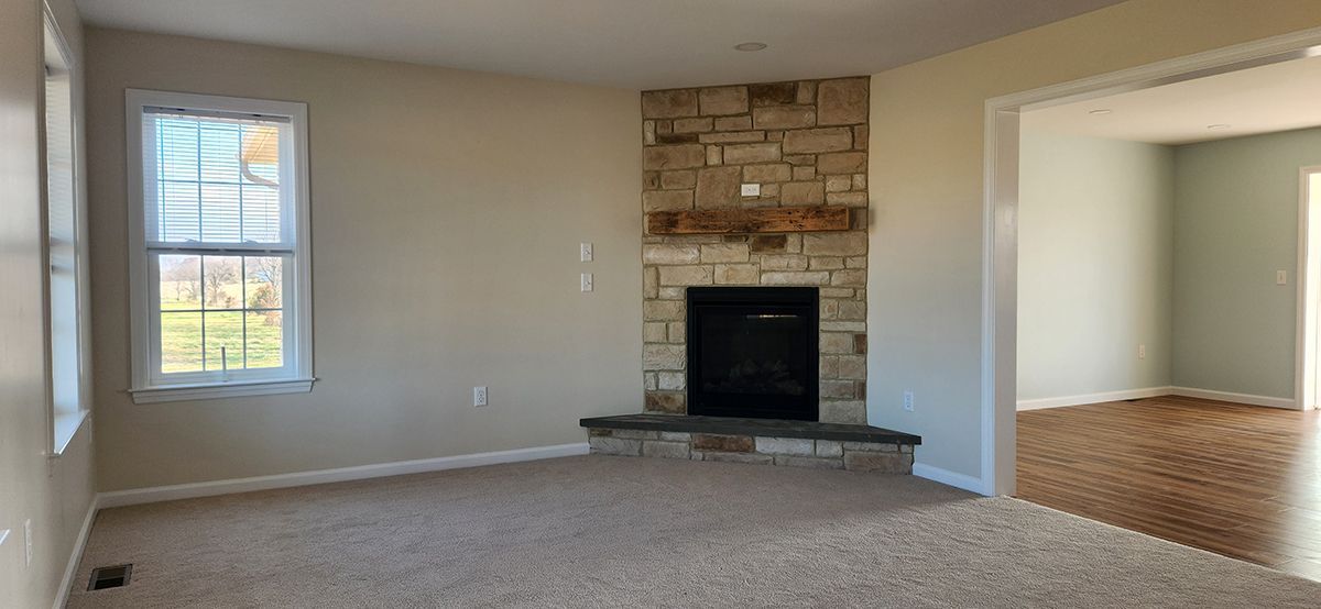 An empty living room with a fireplace and a window.
