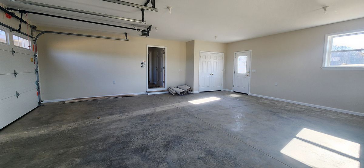 An empty garage with a garage door open to house, closet and door to outside