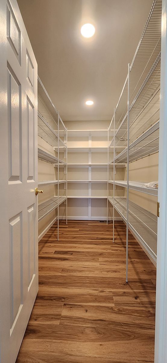 A walk in closet with wooden floors and shelves.