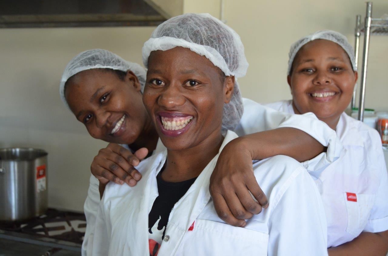 Happy women workers in the Black Mamba factory in Eswatini making jam, marmalade and chilli products for True origin in the UK