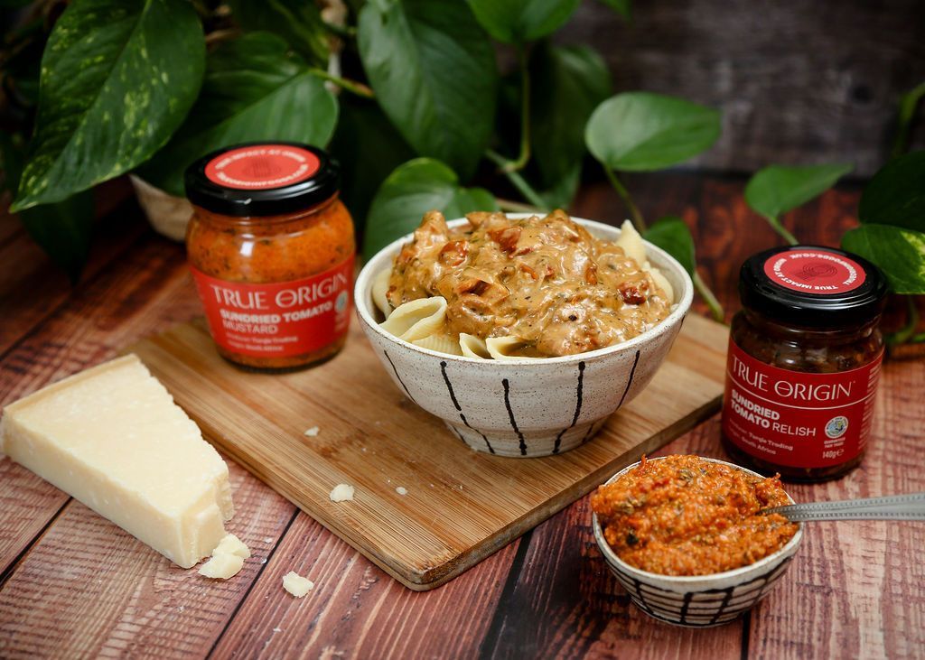 A jar of Sundried Tomato Mustard next to a bowl of Tuscan Chicken