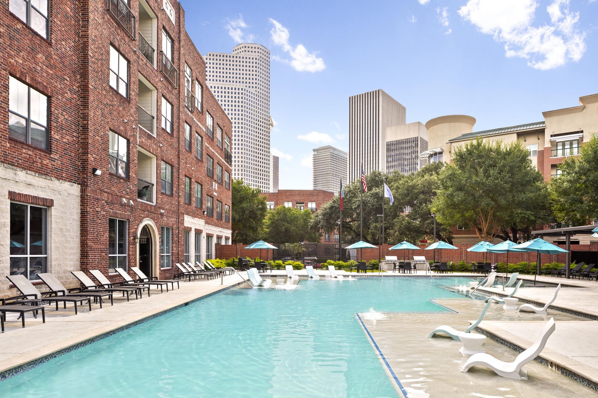 Swimming pool with lounge chairs and umbrellas near a residential building