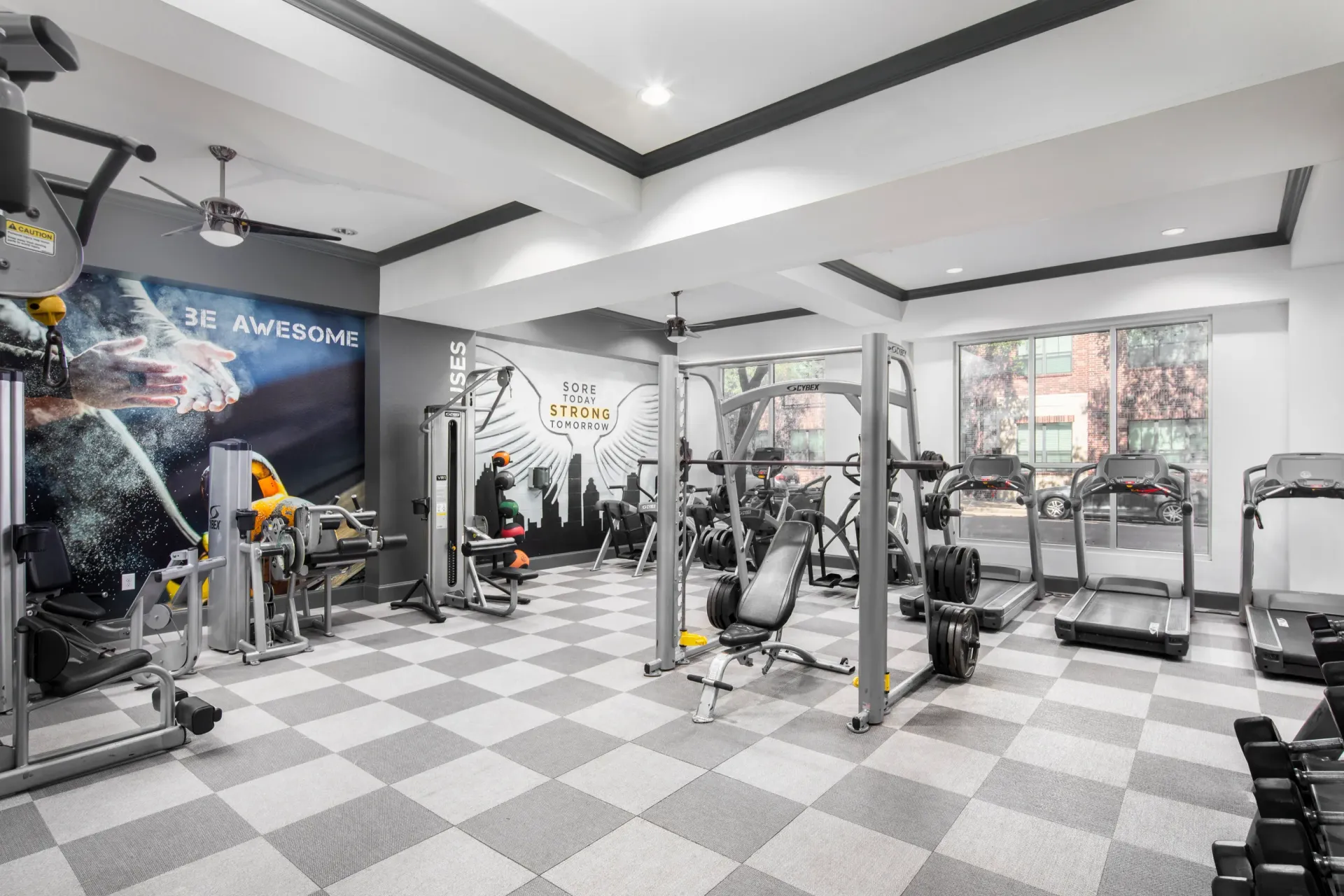 Interior view of a modern gym with exercise equipment and motivational wall art.
