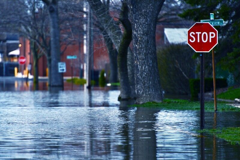 A stop sign is in the middle of a flooded street.