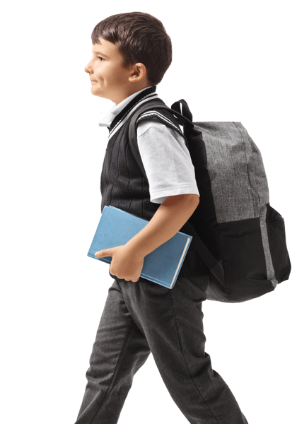 A young boy with a backpack is walking and holding a book.