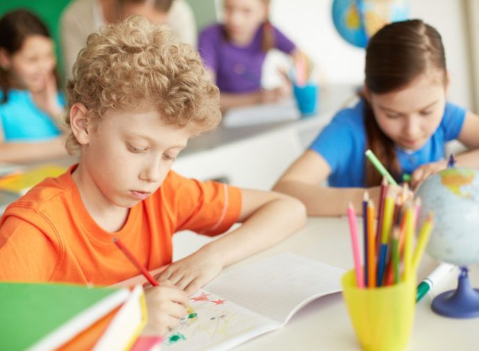 A boy and a girl are sitting at a desk in a classroom.