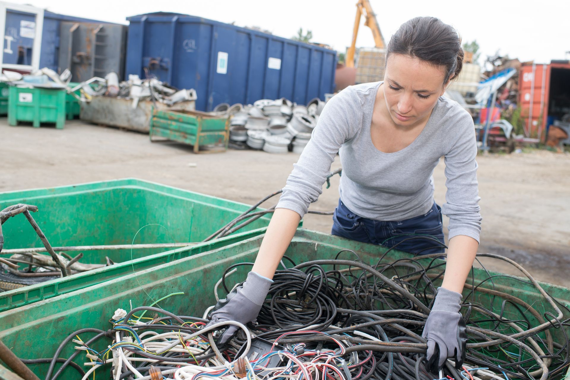 Person in blue gloves sorting recycling. Cardboard and paper materials are visible.