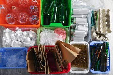 Overhead view of various recycling bins with sorted items: plastic bottles, glass, paper, and food containers. Overhead view of various recycling bins with sorted items: plastic bottles, glass, paper, and food containers.