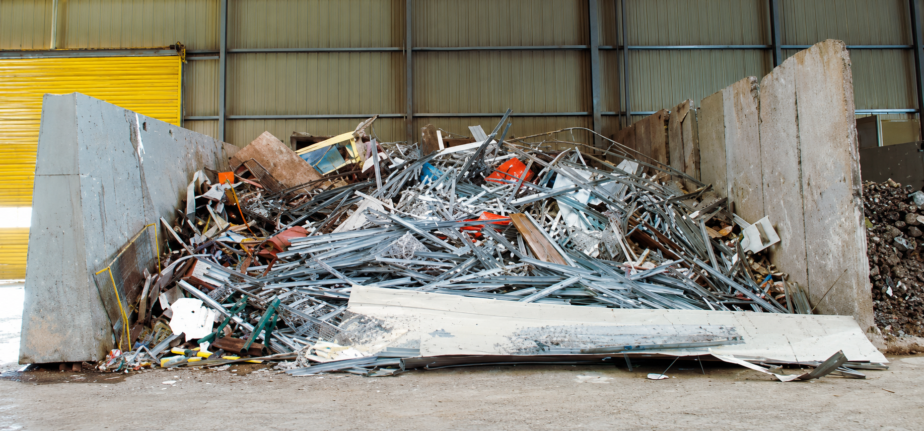 Large pile of shredded industrial scrap steel at a metal recycling center.