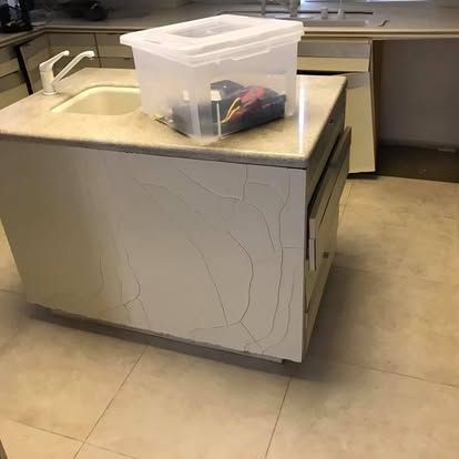 Kitchen island with sink, cracked white panel, and a storage bin on top.