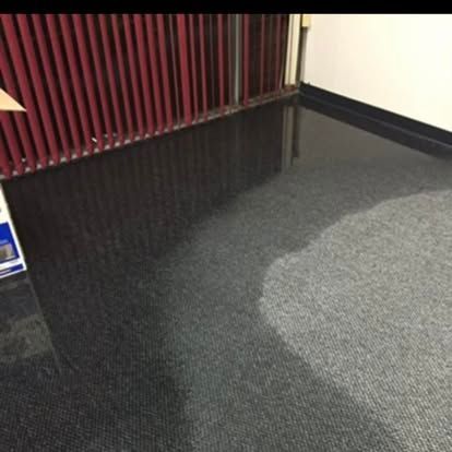 Dark water pooling on office carpet next to a red file cabinet.