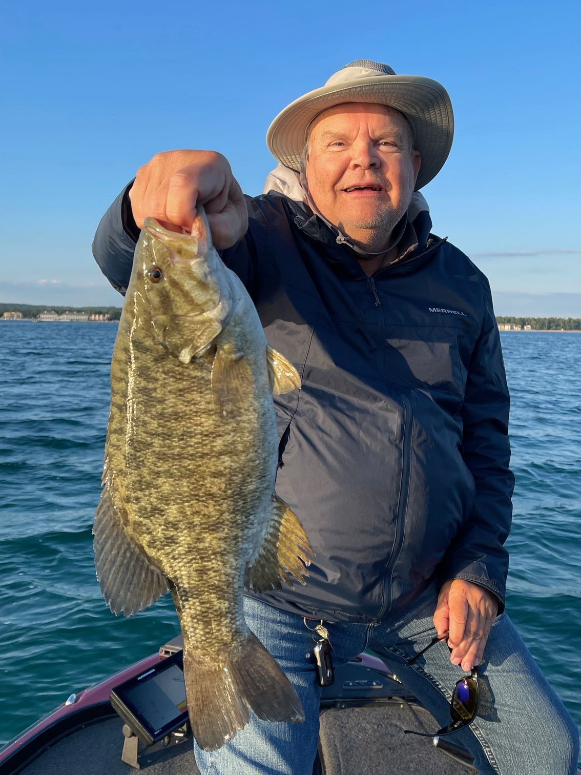 A man is sitting on a boat holding a large fish.