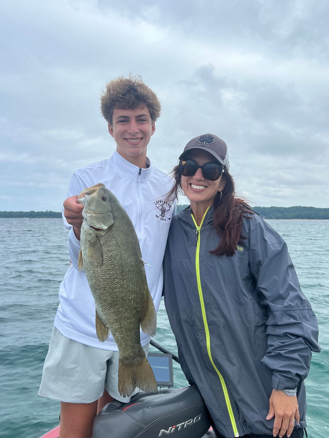 A man and a woman are standing on a boat holding a large fish.