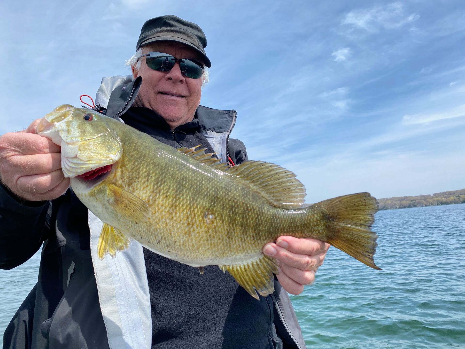 A man is holding a large bass in his hands on a lake.