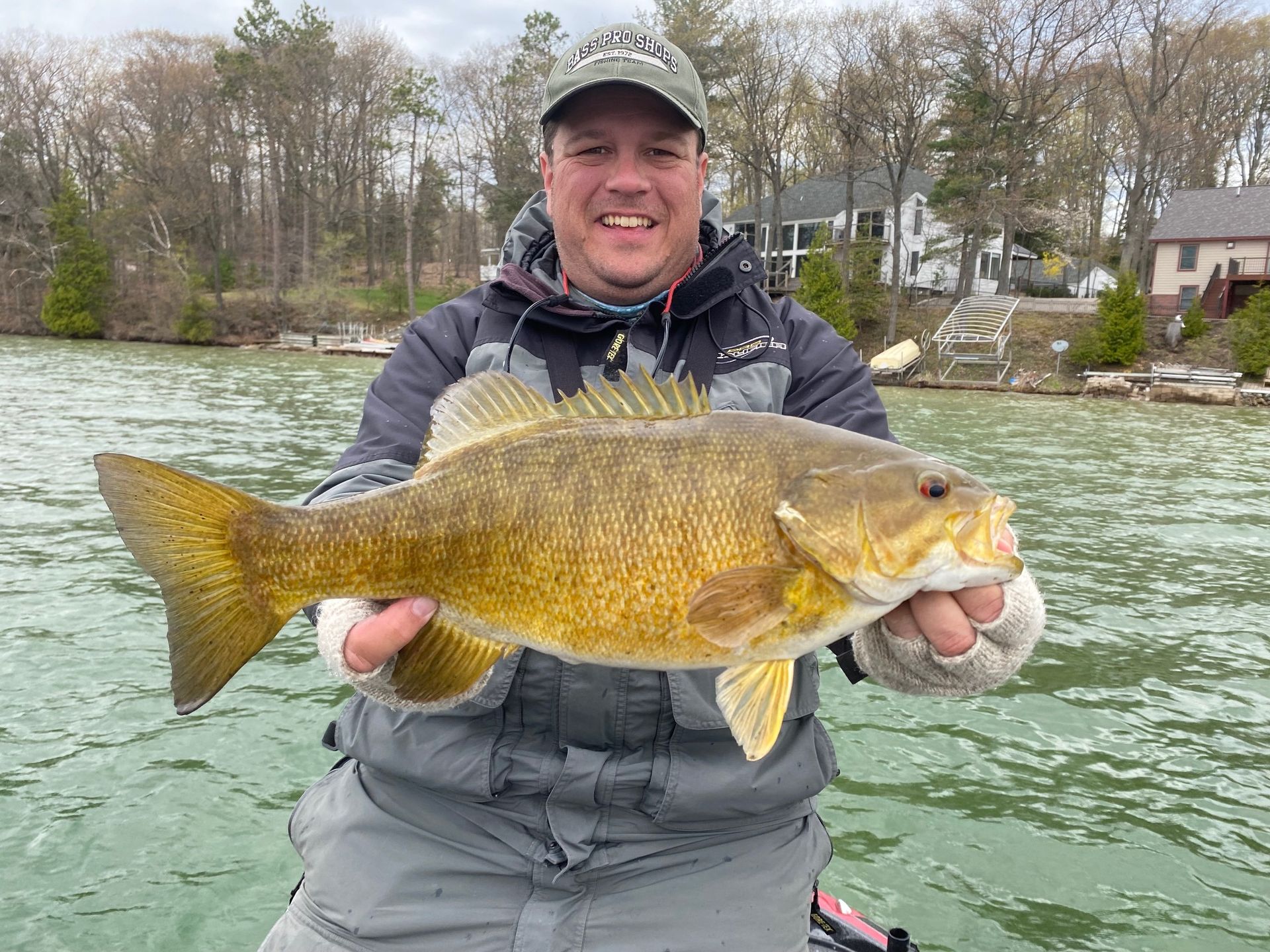 A man is holding a large fish in his hands on a boat.