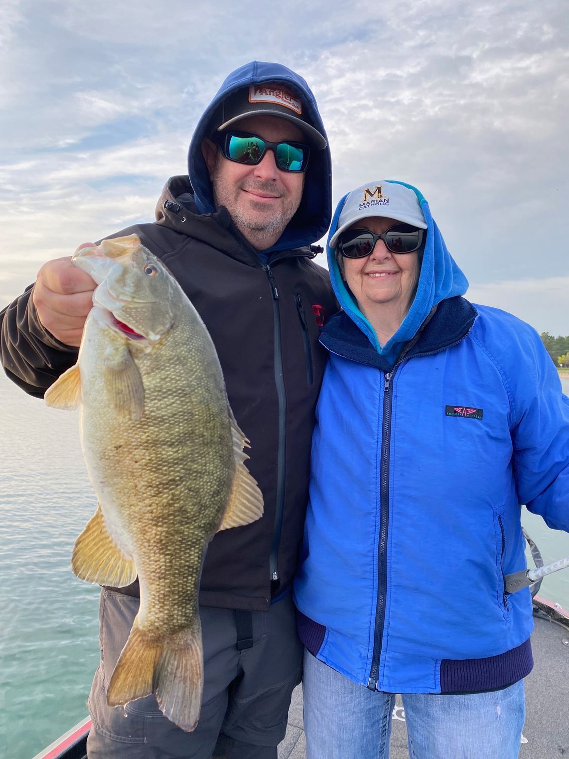 A man and a woman are standing next to each other holding a large fish.