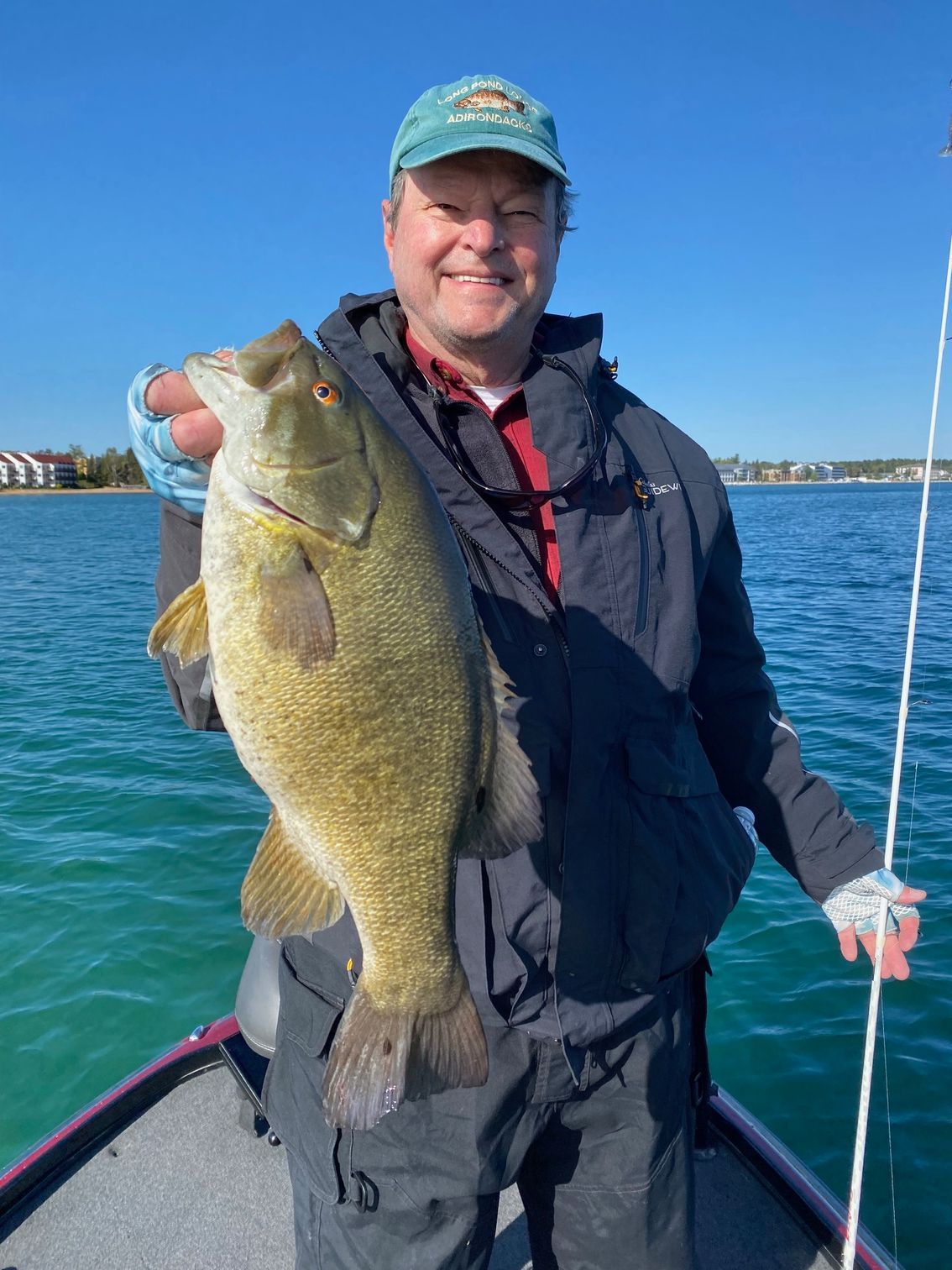 A man is standing in a boat holding a large fish.