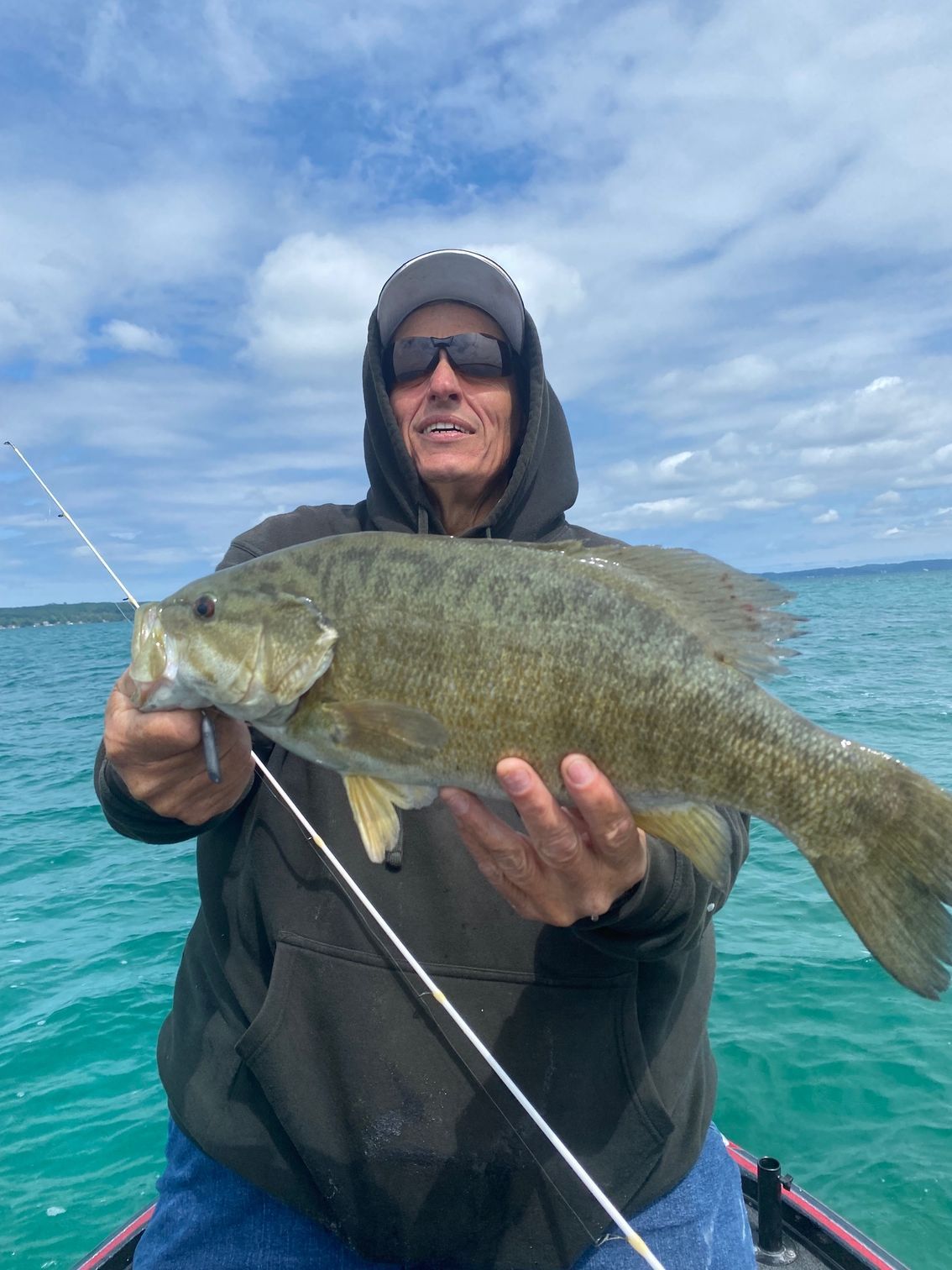 A man in a boat is holding a large fish in his hands.