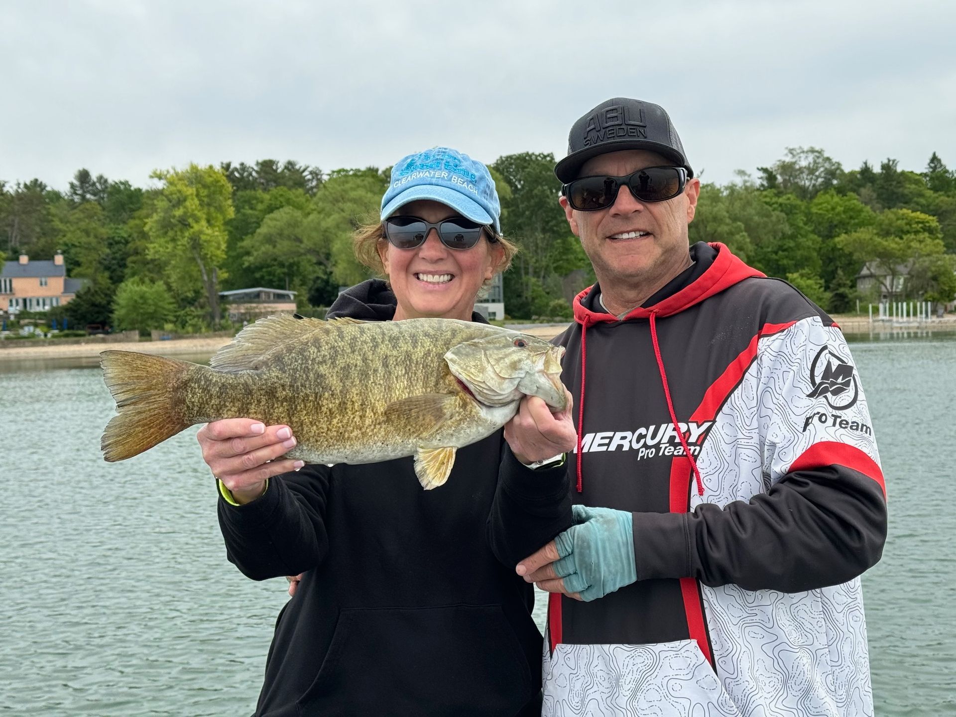 A man and a woman are holding a large fish in their hands.