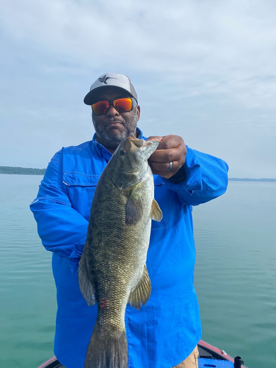 A man in a blue shirt is holding a large fish in his hands.