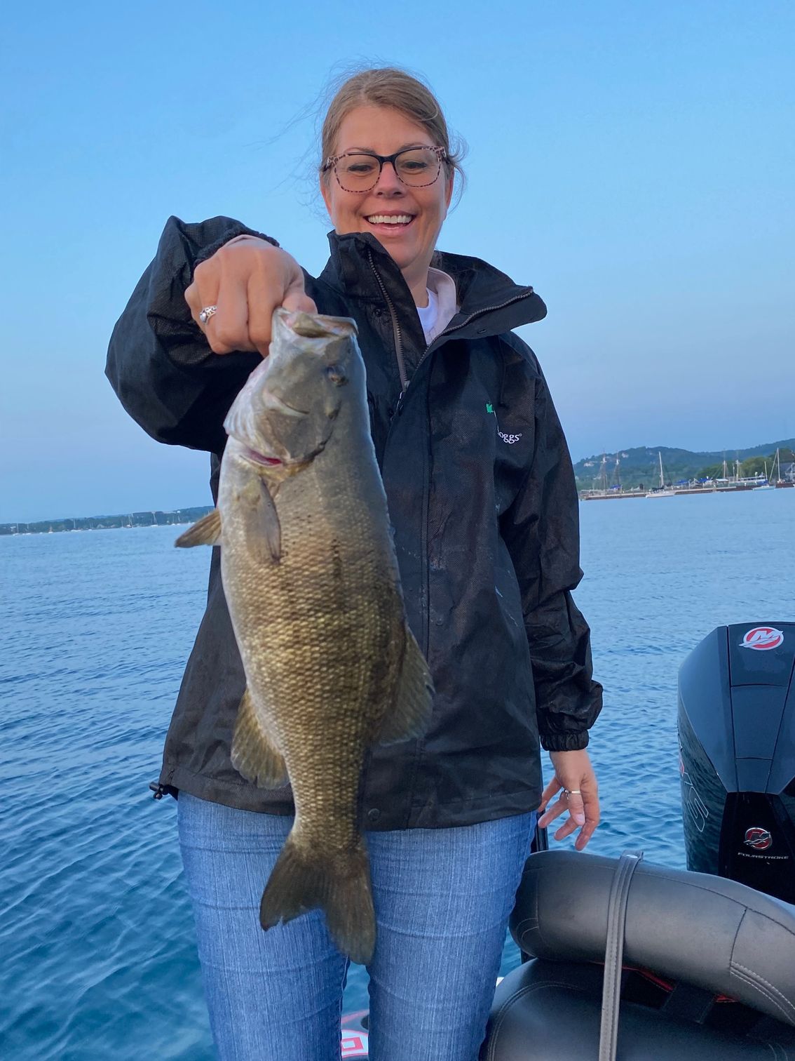A woman is holding a large fish on a boat.