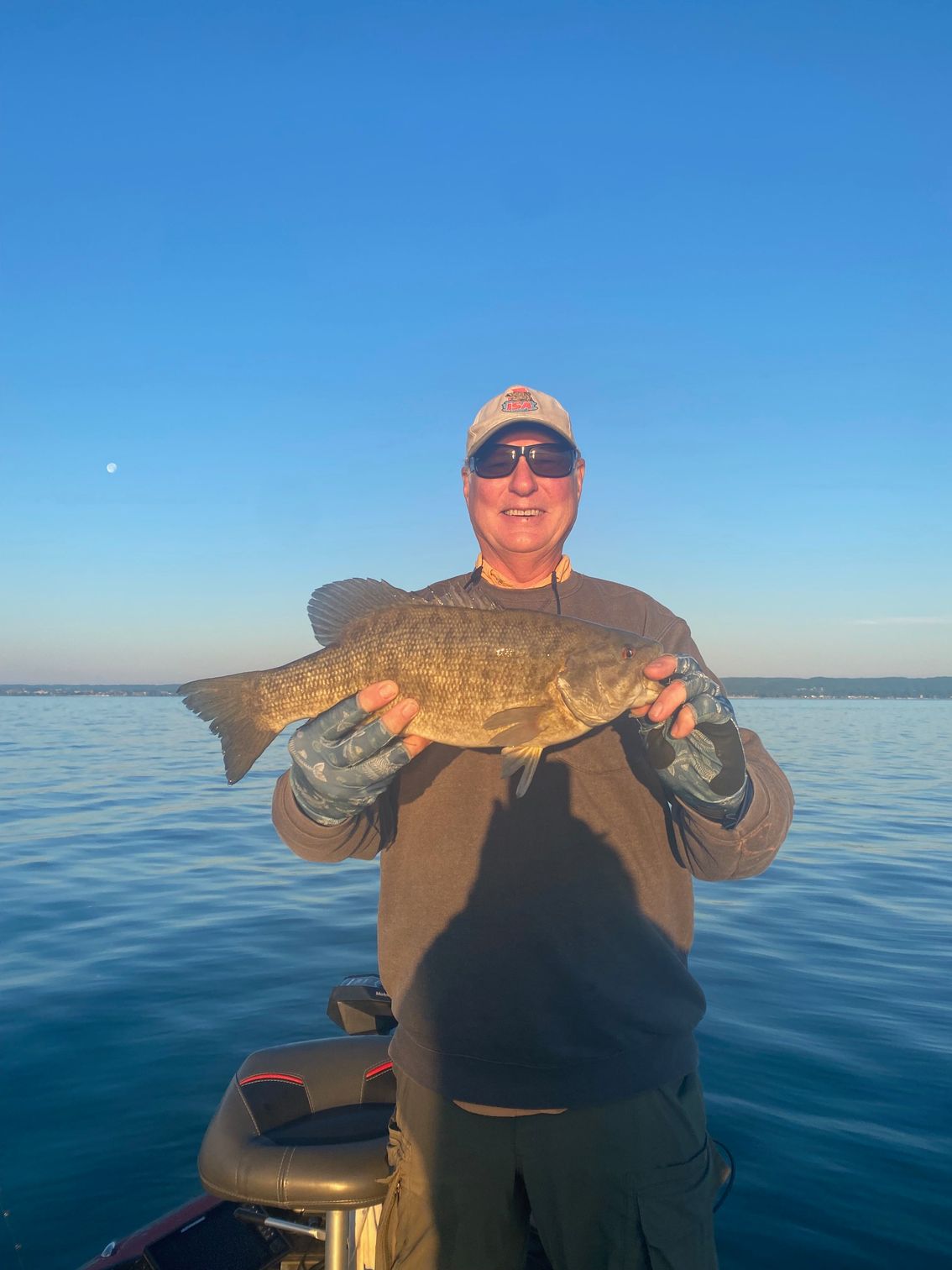 A man is standing on a boat holding a large fish.