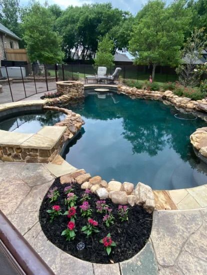 A large swimming pool surrounded by rocks and flowers