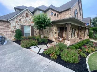 A large brick house with a lush green garden in front of it.