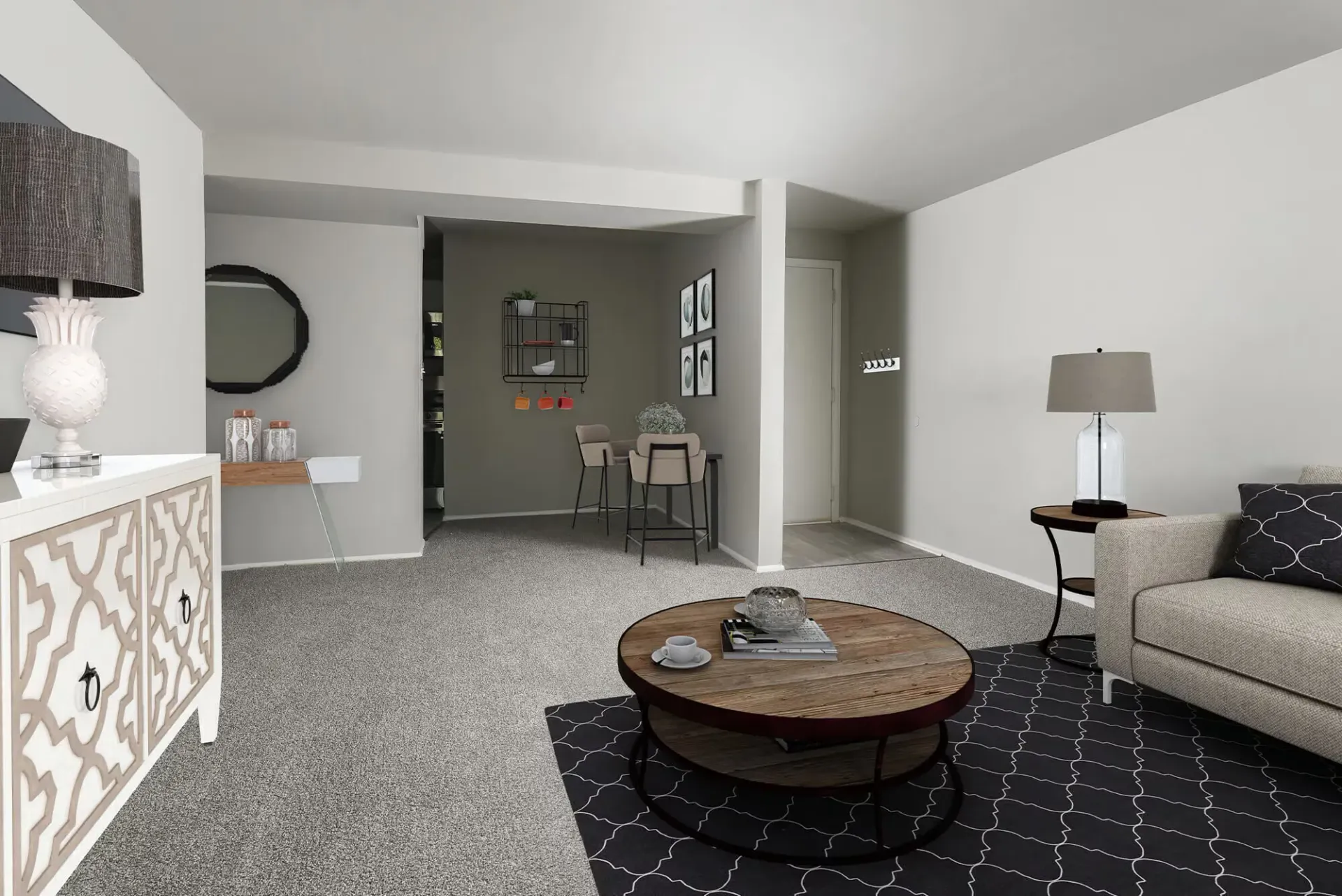 Neutral-toned living room in an apartment with a beige sofa, round coffee table, and gray rug.