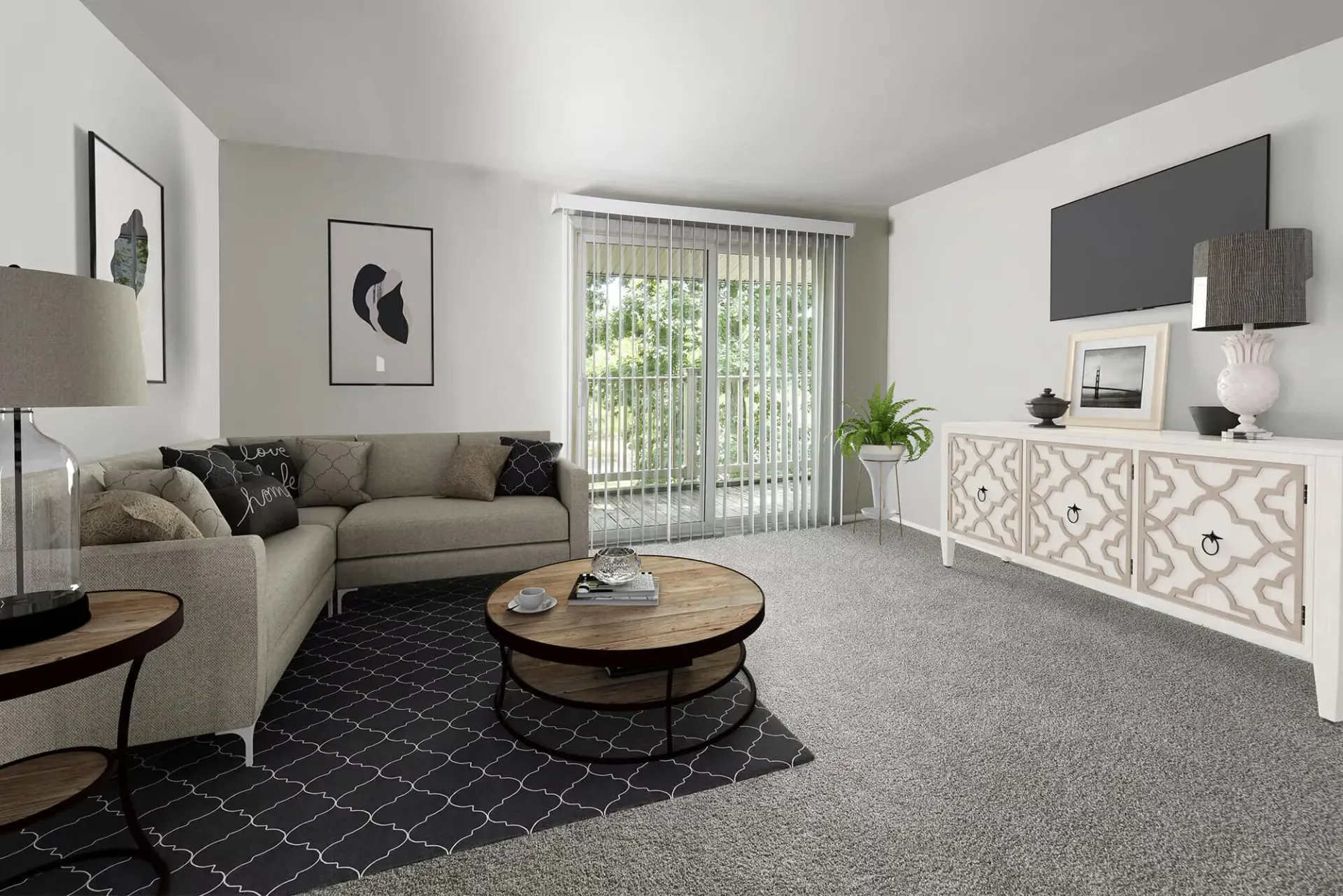 Bright apartment living room with a beige sectional, round coffee table, and a white patterned console.